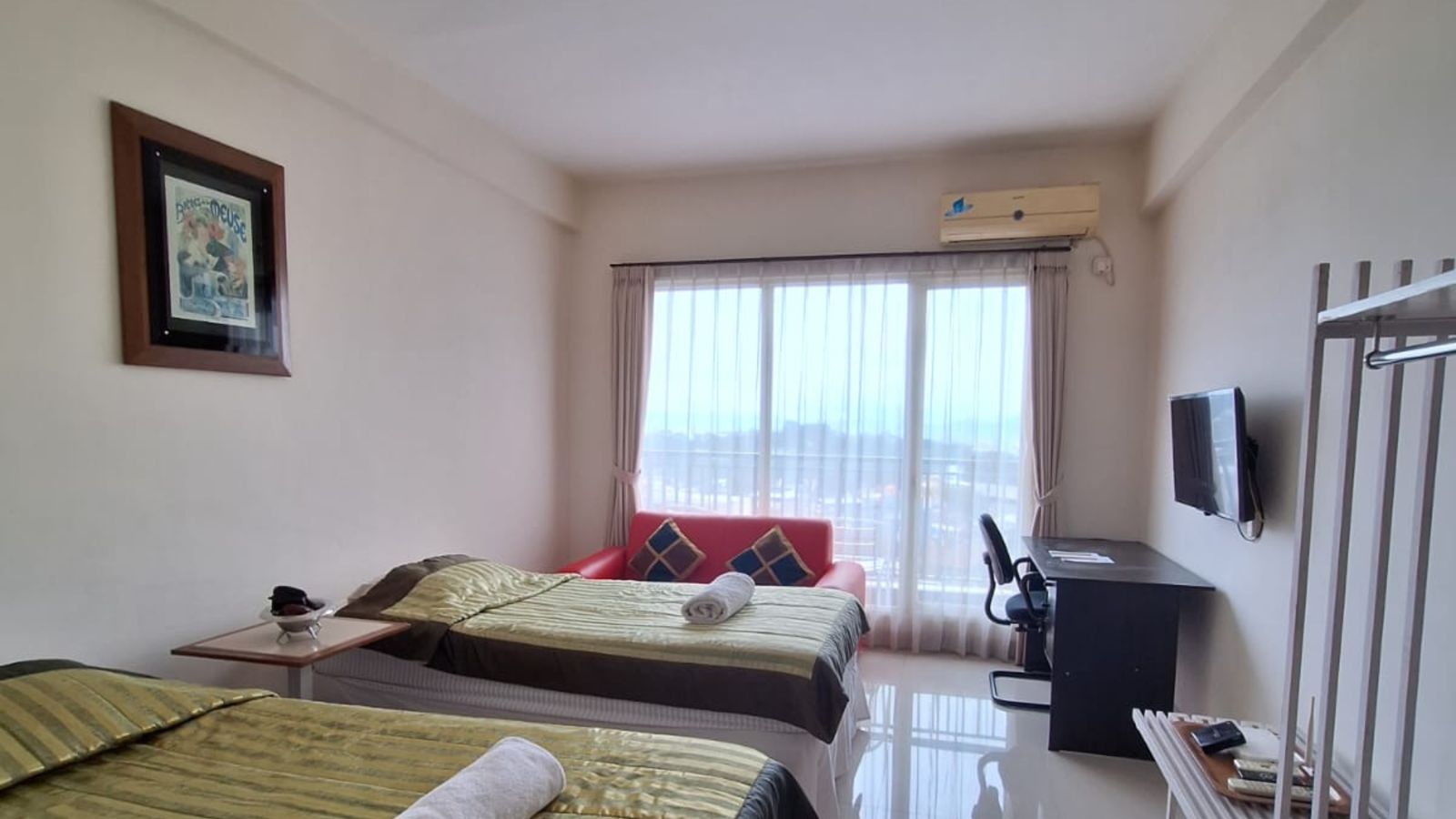 Sebelum: kamar dengan seprai hijau keemasan, sofa merah, lukisan berbingkai, dan meja kerja hitam