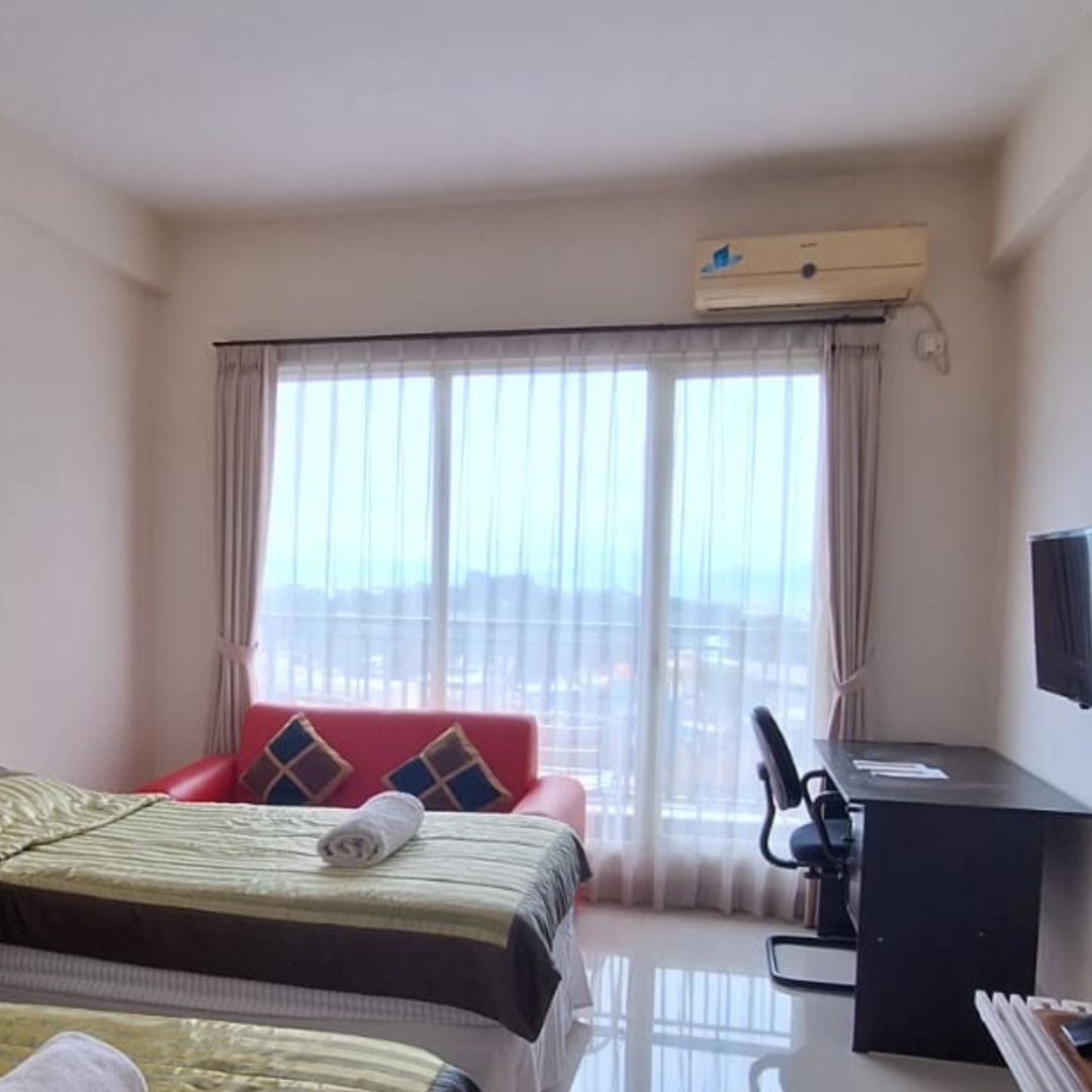 Sebelum: kamar yang sama dengan seprai hijau keemasan, sofa merah, dan meja kerja hitam